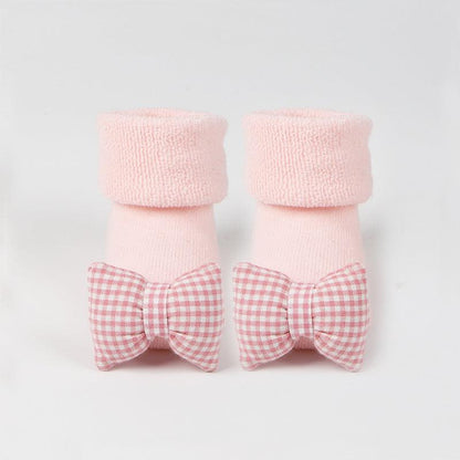 Cotton baby socks with rubber anti-slip soles, pink with adorable bow design.