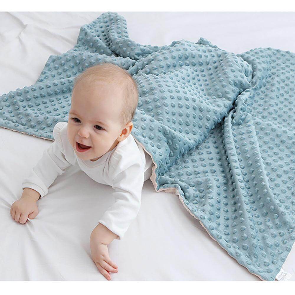 Baby lying on ultra soft dotted blue blanket.